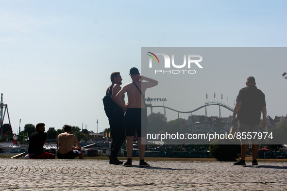 Two young men stands  along the Rhine river in the mid of day in Duesseldorf, Germany on July 18, 2022 as a heat wave reaches to Germany 