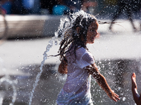 A young girl playswith the water of a fountain in city center of  Duesseldorf, Germany on July 18, 2022 as a heat wave reaches to Germany (