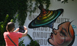 A woman takes a picture of a mural in Rzeszow.On Thursday, July 21, 2022, in Rzeszow, Sub...