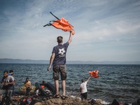 Volunteers waves lifejackets to direct boats to the safe areas to land on the shores of Lesbos, Greece, on September 26, 2015.  (
