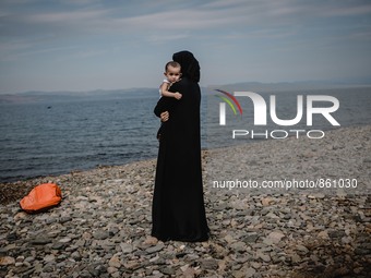 A women holds her child while looking back towards the sea she and her family just crossed from Turkey, in Lesbos, Greece, on September 26,...