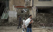 An Iranian couple carrying their belongings in plastic bags as they walk past destroyed bu...
