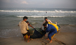 Palestinian fishermen collect caught fish from their net, on a beach in Beit Lahia near th...
