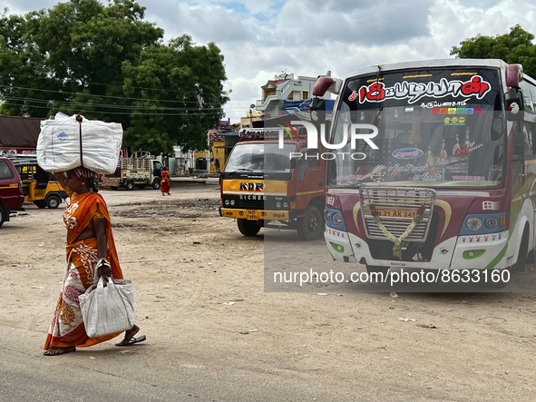 Woman carries a heavy bundle atop her head near the bus stand in Nilakkottai (Nilakottai), Tamil Nadu, India, on May 18, 2022.  