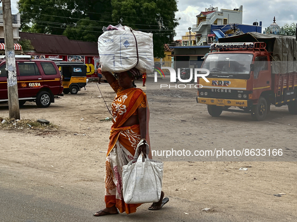 Woman carries a heavy bundle atop her head near the bus stand in Nilakkottai (Nilakottai), Tamil Nadu, India, on May 18, 2022. 