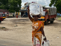 Woman carries a heavy bundle atop her head near the bus stand in Nilakkottai (Nilakottai), Tamil Nadu, India, on May 18, 2022. (