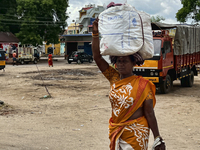 Woman carries a heavy bundle atop her head near the bus stand in Nilakkottai (Nilakottai), Tamil Nadu, India, on May 18, 2022. (