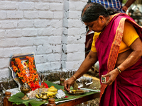 Woman lights a lamp at a small shrine dedicated to Goddess Attukal Devi seen along the roadside during the final day of the 10 day-long Attu...