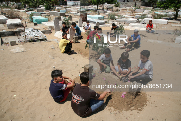Palestinian children sit next to the graves of their five friends from the Najm family who were killed during the last fight between Gaza an...