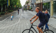 People walking and cycling by the old town streets during the rainy summer day are seen in...