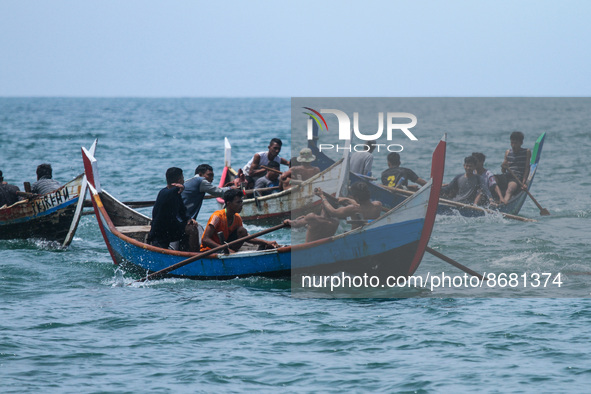 Participants row a traditional boat during a race to celebrate the 77th Anniversary at Ujong Blang Beach in Lhokseumawe, on August 17, 2022,...