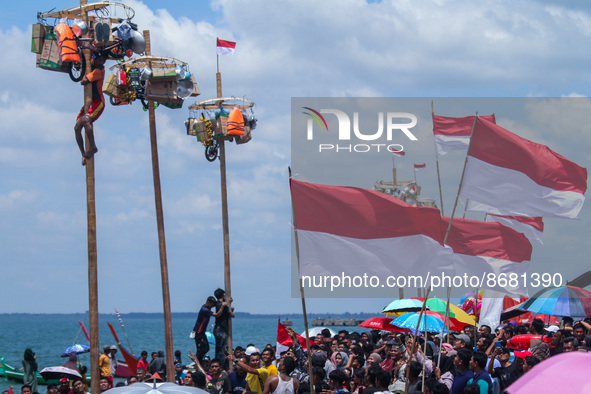 Participants struggle to climb a greasy pole to claim prizes in the "Panjat Pinang" race during the celebration of Indonesia's 77th Independ...