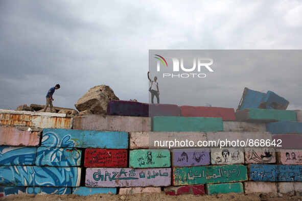 A Palestinian youth takes a selfie during a windy day  on a big stone wall on Oct. 25, 2015. that was painted by local artists at the sea po...