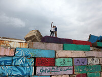 A Palestinian youth takes a selfie during a windy day  on a big stone wall on Oct. 25, 2015. that was painted by local artists at the sea po...