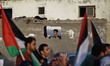 A Palestinian boy looks out through the window of his house to a march calling for an end...