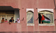 A Palestinian boy looks out through the balcony of their house to a march calling for an e...