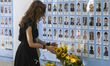 A woman lays flowers to Memory Wall of the Fallen Defenders of Ukraine in the russian - Uk...