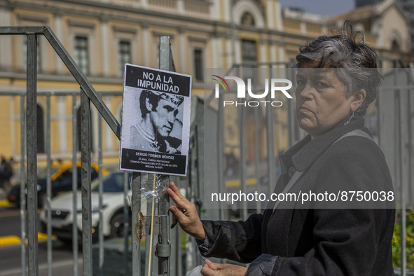 A woman pastes a photo of a detainee disappeared during Pinochet's civil-military dictatorship on the street of Santiago de Chile, on August...