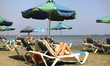 A girl smokes a cigarette while reading a book on the beach in the Mediterranean port of L...