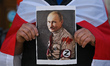 A protester holds a poster with TIME's front page and an image of Russian President, Vladi...