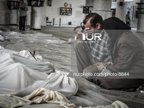 A mother and father weep over their child's body who was killed in a suspected chemical weapons attack on the Damascus suburb of Ghouta, in...