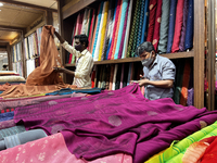 Salesmen cut cloth for customers to be made into ladies churidar suits and sarees at a textile shop in Thiruvananthapuram, Kerala, India, on...