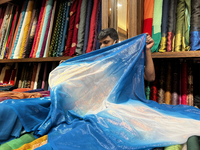 Salesman measures cloth for a customer to be used for a saree at a textile shop in Thiruvananthapuram, Kerala, India, on May 22, 2022. (