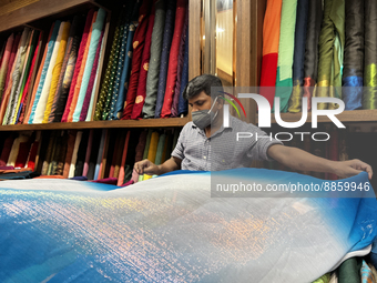 Salesman measures cloth for a customer to be used for a saree at a textile shop in Thiruvananthapuram, Kerala, India, on May 22, 2022. (