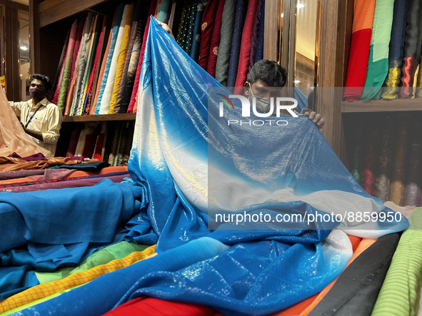 Salesmen measure cloth for a customers to be used for sarees at a textile shop in Thiruvananthapuram, Kerala, India, on May 22, 2022. 