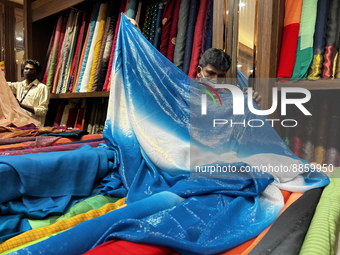 Salesmen measure cloth for a customers to be used for sarees at a textile shop in Thiruvananthapuram, Kerala, India, on May 22, 2022. (