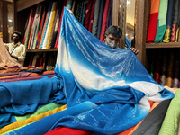 Salesmen measure cloth for a customers to be used for sarees at a textile shop in Thiruvananthapuram, Kerala, India, on May 22, 2022. (