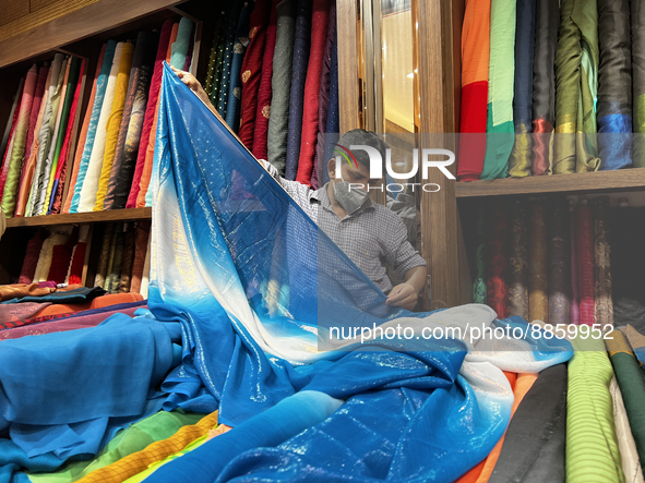 Salesman measures cloth for a customer to be used for a saree at a textile shop in Thiruvananthapuram, Kerala, India, on May 22, 2022. 