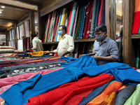 Salesmen cut cloth for customers to be made into ladies churidar suits and sarees at a textile shop in Thiruvananthapuram, Kerala, India, on...