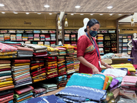 Salesgirl folding churidar suits at a textile shop in Thiruvananthapuram, Kerala, India, on May 22, 2022. (