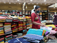 Salesgirl folding churidar suits at a textile shop in Thiruvananthapuram, Kerala, India, on May 22, 2022. (