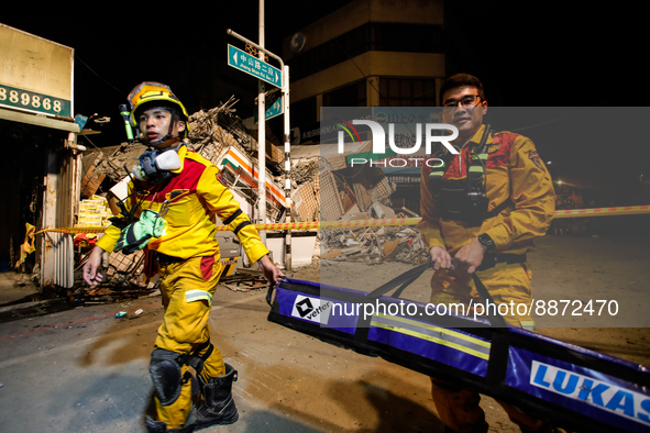 Rescuers carrying equipment  outside the wreckage of a collapsed residential building after a magnitude 6.8 earthquake strikes Taiwan, in Yu...
