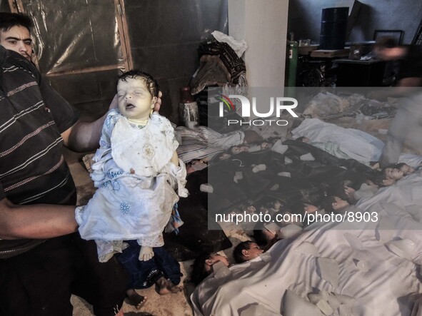 A deceased baby is held in front of a morgue filled with children  after that about 1.300 people were killed by nerve gas on the Damascus su...