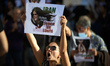An Iranian womanshouts while holding a drawing depicting Mahsa Amini reading 'Iran, Women,...
