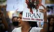An Iranian woman shouts while holding a drawing of Mahsa Amini and the words 'Women, Life,...