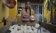 A member of the Mejía family holds a chocolate skull and a decorated sugar skull inside a...
