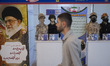 An Iranian visitor walks past mannequins decorated with Military safety equipments at a bo...