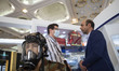 Two unidentified men talk to each other while standing next to a mannequin decorated with...