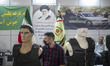 An unidentified Iranian man wearing a protective face mask sits next to mannequins decorat...