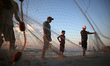 Palestinian fishermen pulling their net along a beach in Gaza City at sunset, on October 1...