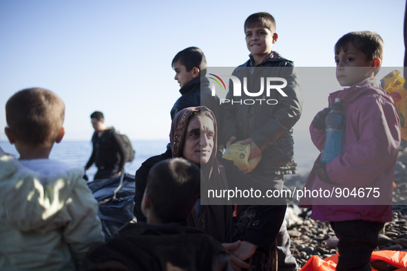 A mother and her children stand as refugees and migrants riding a dinghy reach the shores of the Greek island of Lesbos after crossing the A...