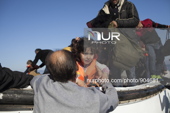 A man carries a child as refugees and migrants riding a dinghy reach the shores of the Greek island of Lesbos after crossing the Aegean Sea...