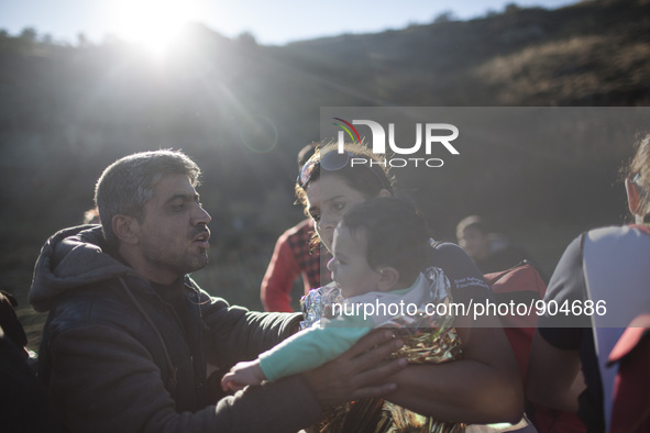 A man comforts his son as refugees and migrants riding a dinghy reach the shores of the Greek island of Lesbos after crossing the Aegean Sea...