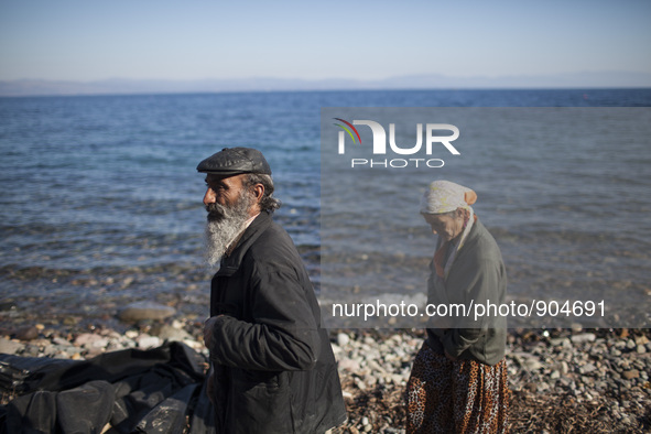 A couple of Afghans walk on a beach of Lesbos after refugees and migrants riding a dinghy reached the shores of the Greek island after cross...