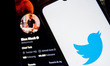 In this photo illustration a Twitter logo seen displayed on a smartphone screen with Elon...