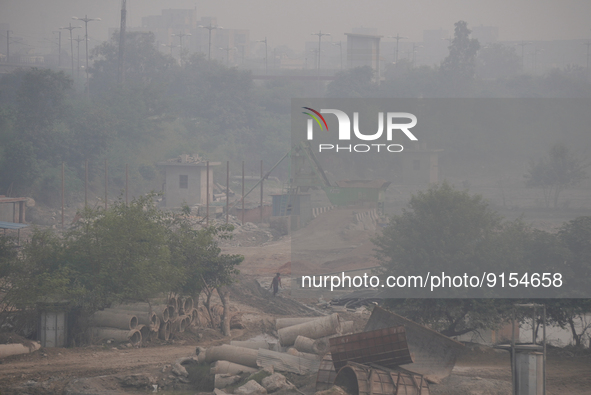A worker walks past a construction site enveloped in a thick layer of smog and haze in New Delhi, India on November 3, 2022. Delhi's air qua...